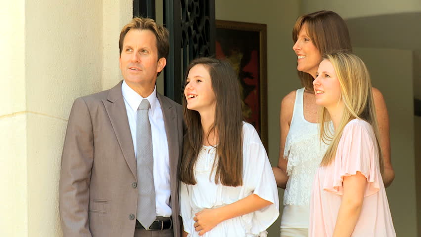 Caucasian Father Being Greeted By Wife Teenage Daughters On Return From Business Trip Stock