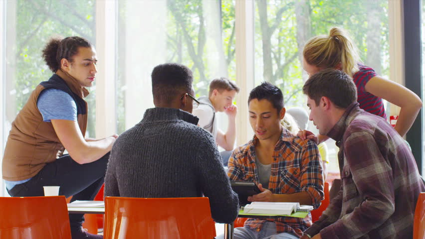 Cheerful diverse student group chatting and working together in college study area