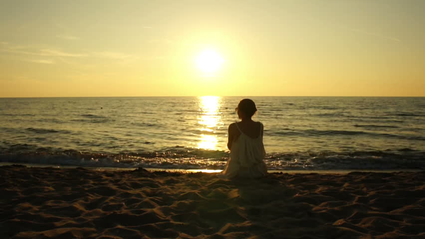 Woman Sitting On A Sand Beach In Front Of Sunset And Ocean In Summer ...